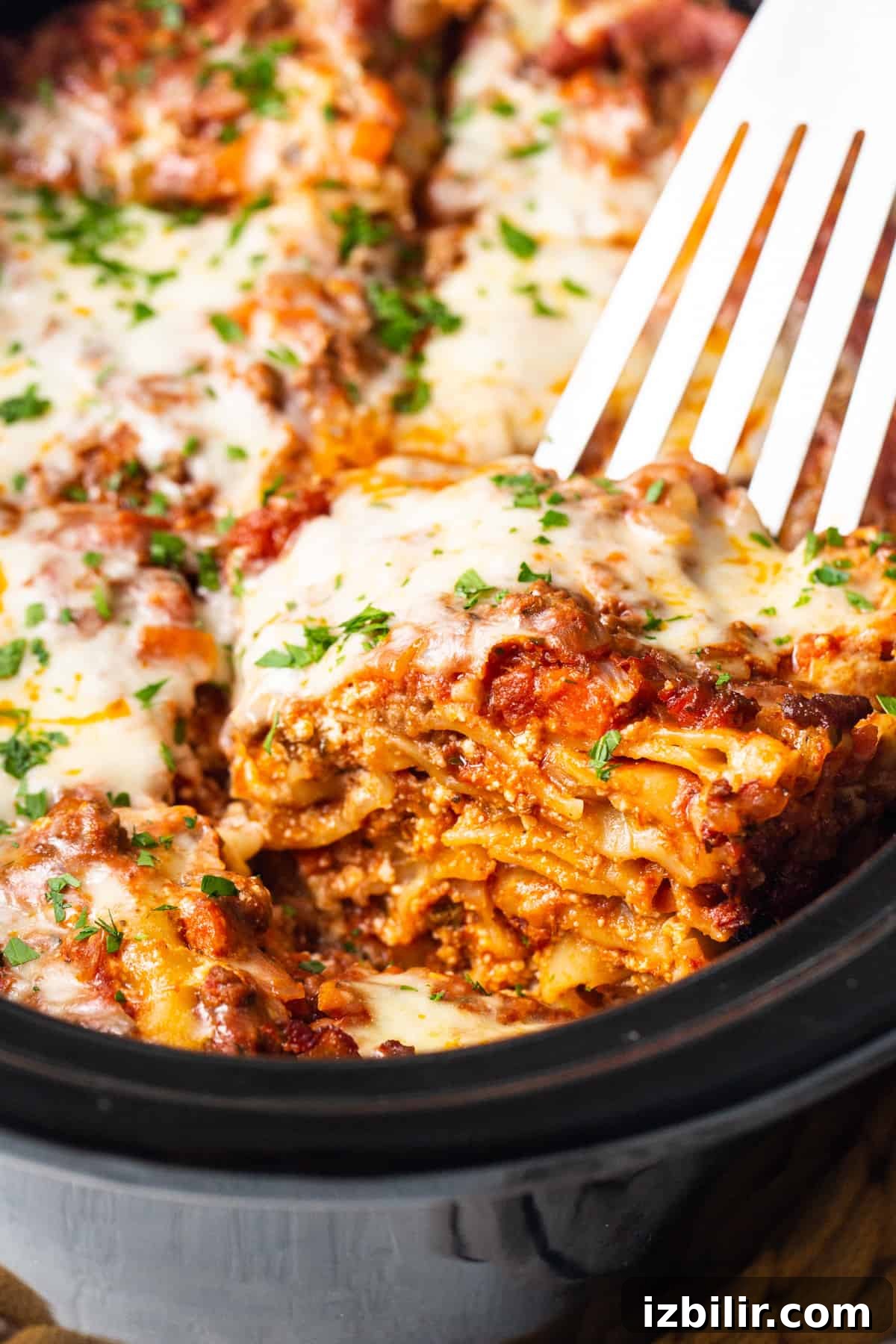 Crockpot Lasagna Recipe: Creamy Slow Cooker Lasagna 2 A close up of a fork in a casserole dish.