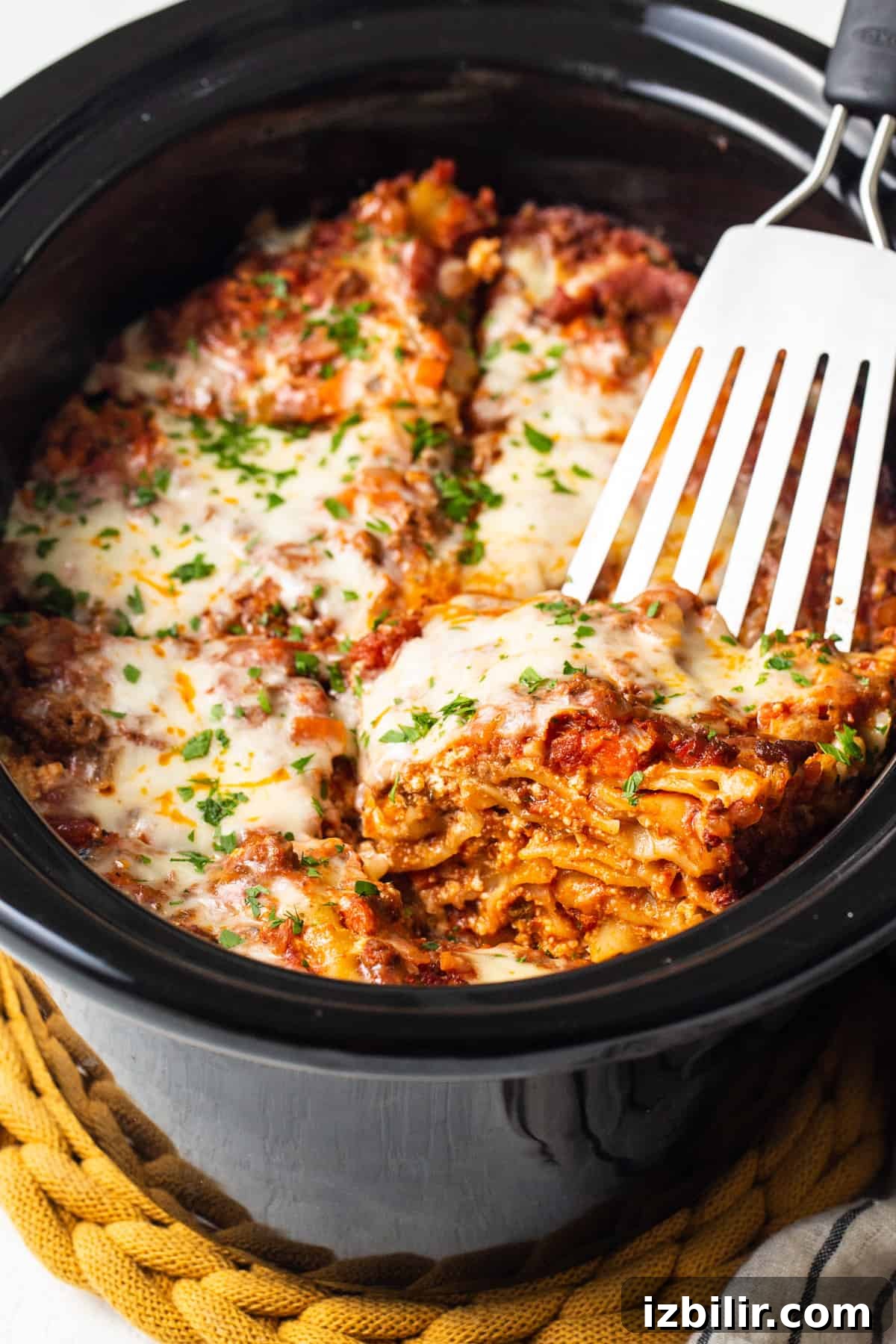 Crockpot Lasagna Recipe: Creamy Slow Cooker Lasagna 5 A close up of a fork in a crock pot filled with lasagna.
