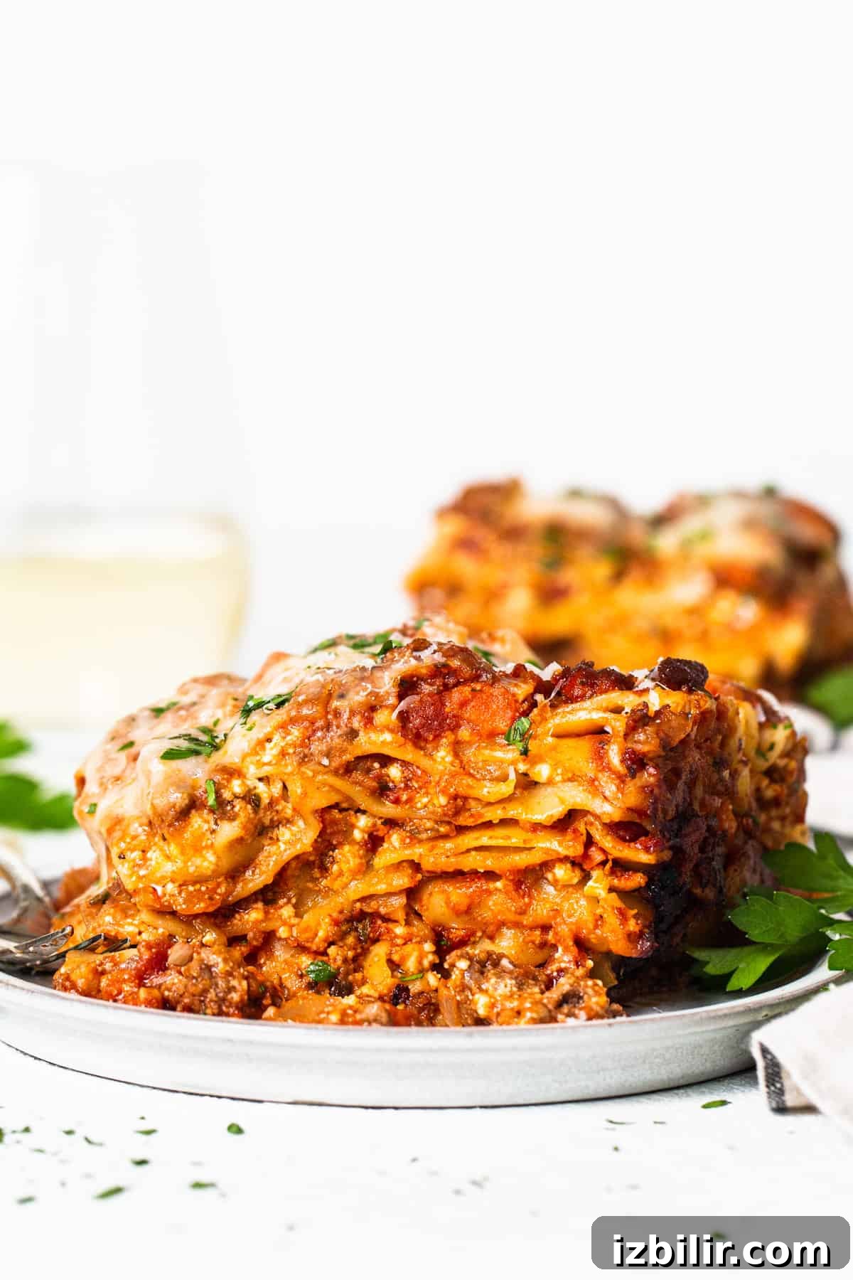 Crockpot Lasagna Recipe: Creamy Slow Cooker Lasagna 6 A white plate topped with lasagna next to a glass of wine.