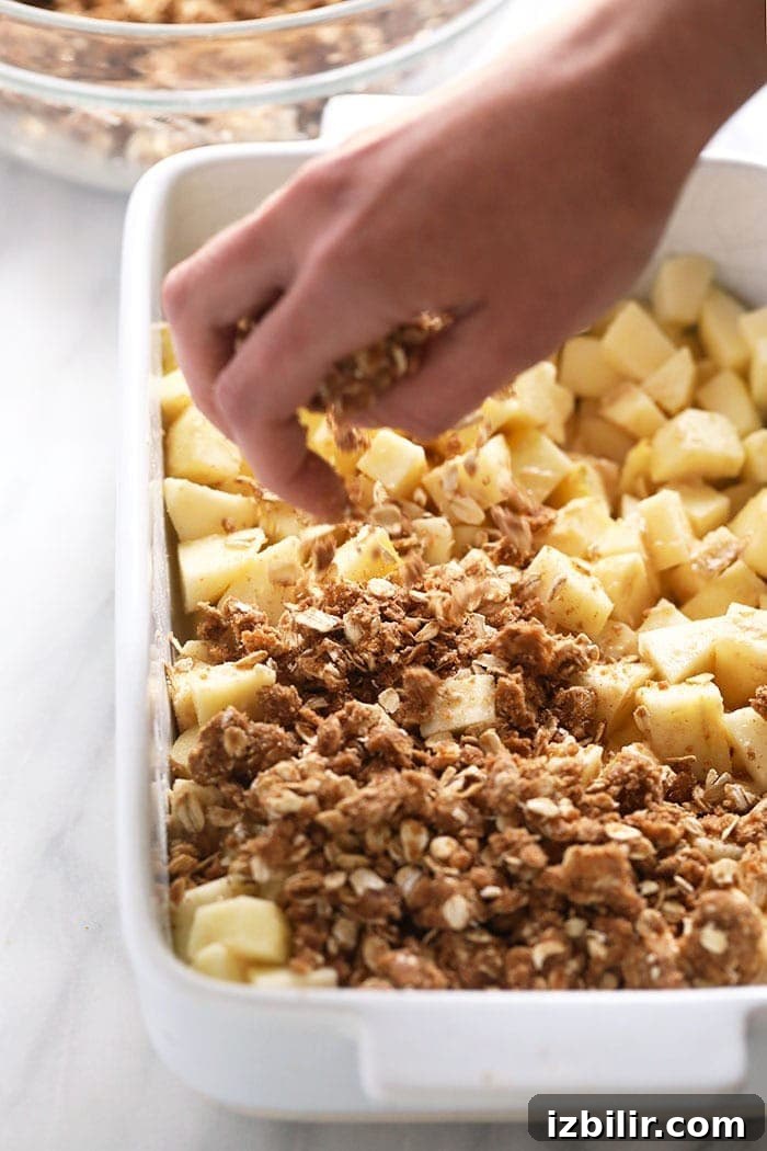 Assembling apple crisp with crumble topping sprinkling crumble topping on apples