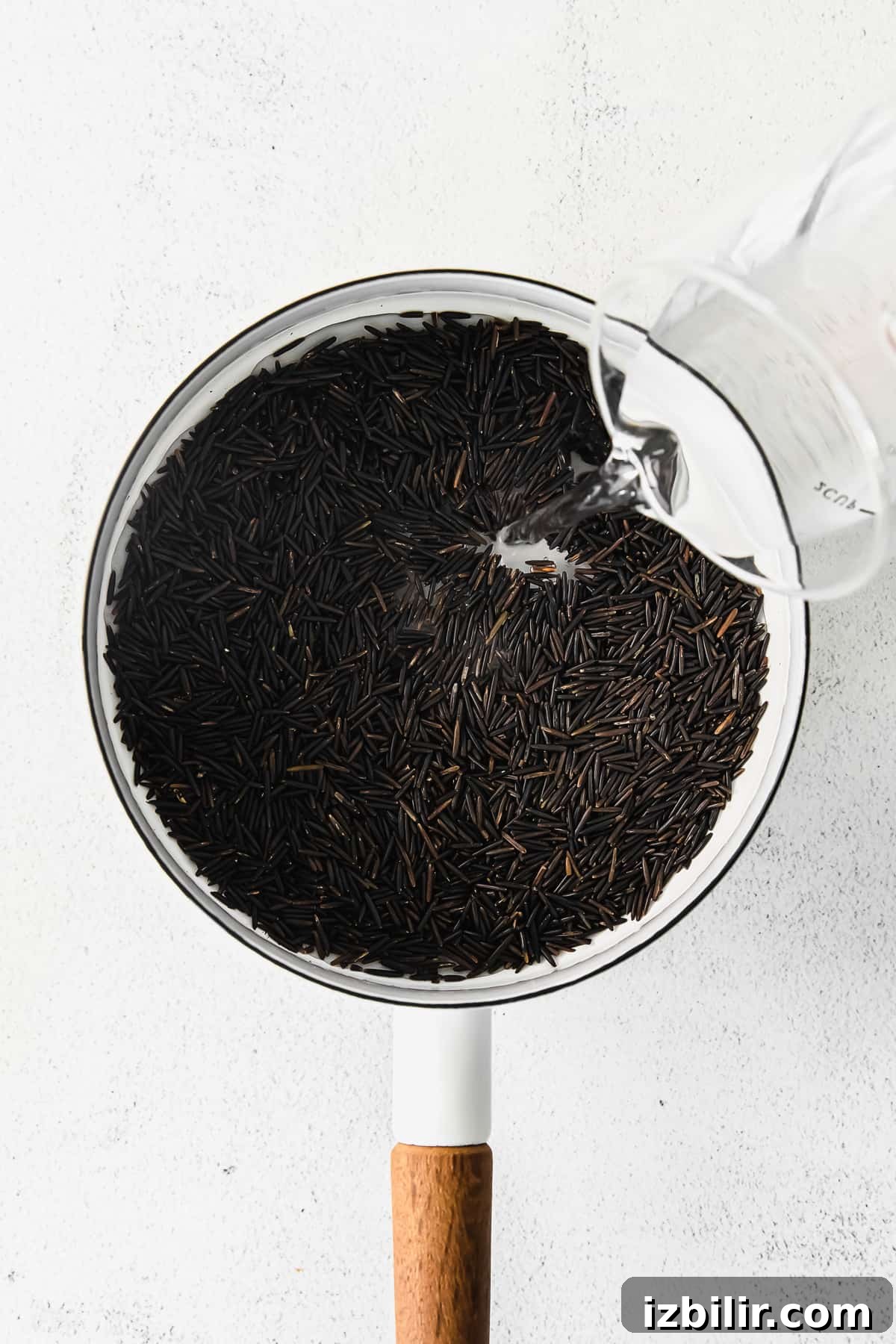 How to Cook Wild Rice: Stovetop, Oven and Rice Cooker Tips 4 Water being poured into a stock pot of dried wild rice
