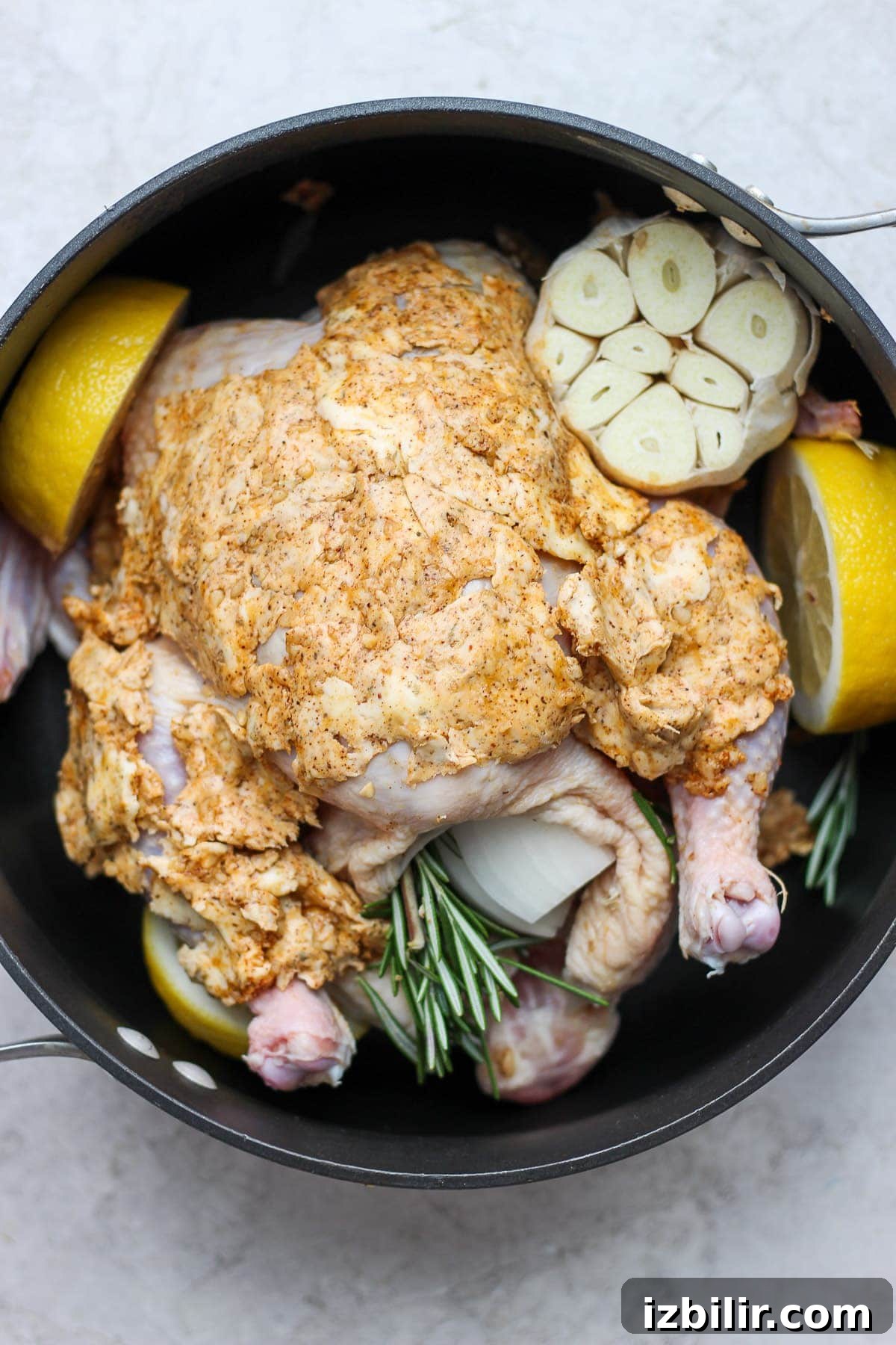 Raw whole chicken prepared in a pan with herbs and lemon. raw whole chicken in pan