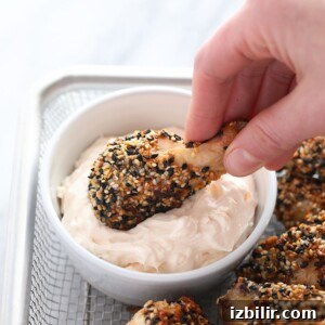 Homemade Everything Bagel Seasoning Recipe 2 a person dipping crispy baked chicken wings in a bowl.