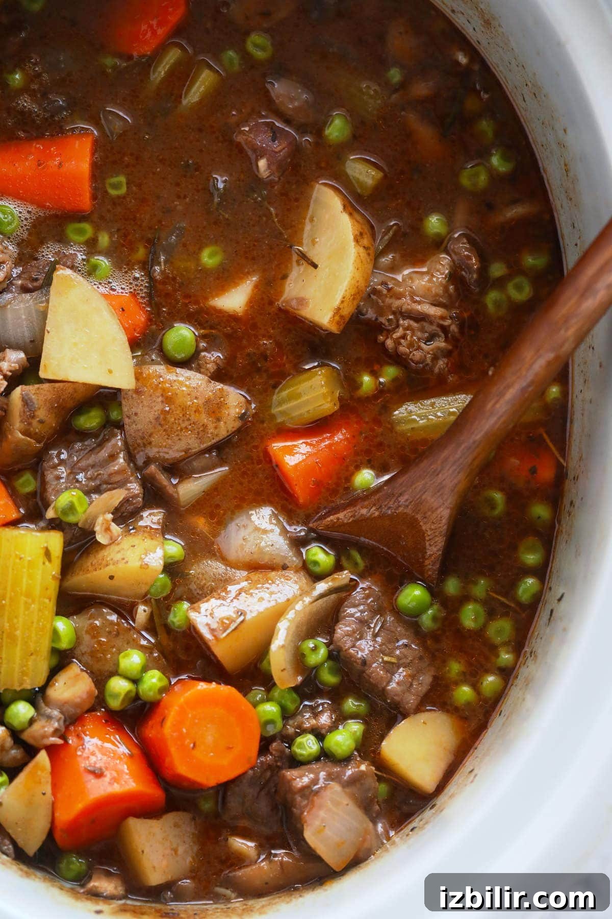 beef stew in the slow cooker being stirred with a spoon