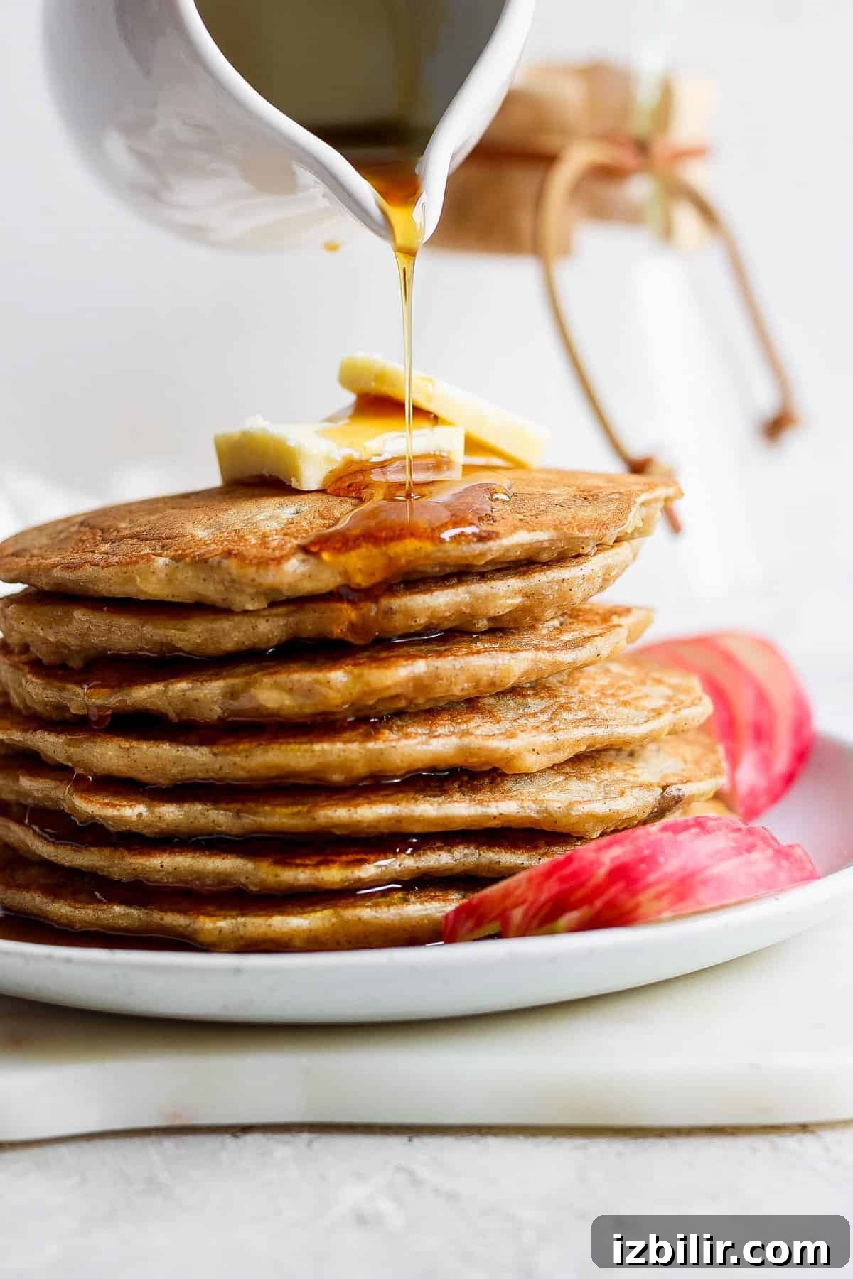 Fluffy Cinnamon Apple Pancakes with Caramel Sauce 2 a stack of pancakes with syrup being poured onto them.