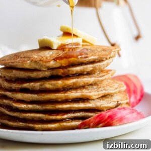 Fluffy Cinnamon Apple Pancakes with Caramel Sauce 11 a stack of pancakes with syrup being poured onto them.
