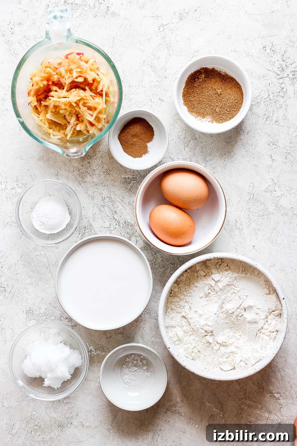Fluffy Cinnamon Apple Pancakes with Caramel Sauce 3 eggs, flour, sugar, and other ingredients are shown on a table.