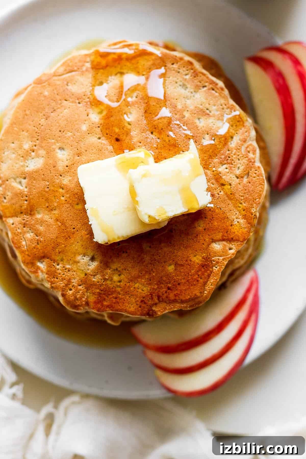 Fluffy Cinnamon Apple Pancakes with Caramel Sauce 5 pancakes with butter and apples on a plate.