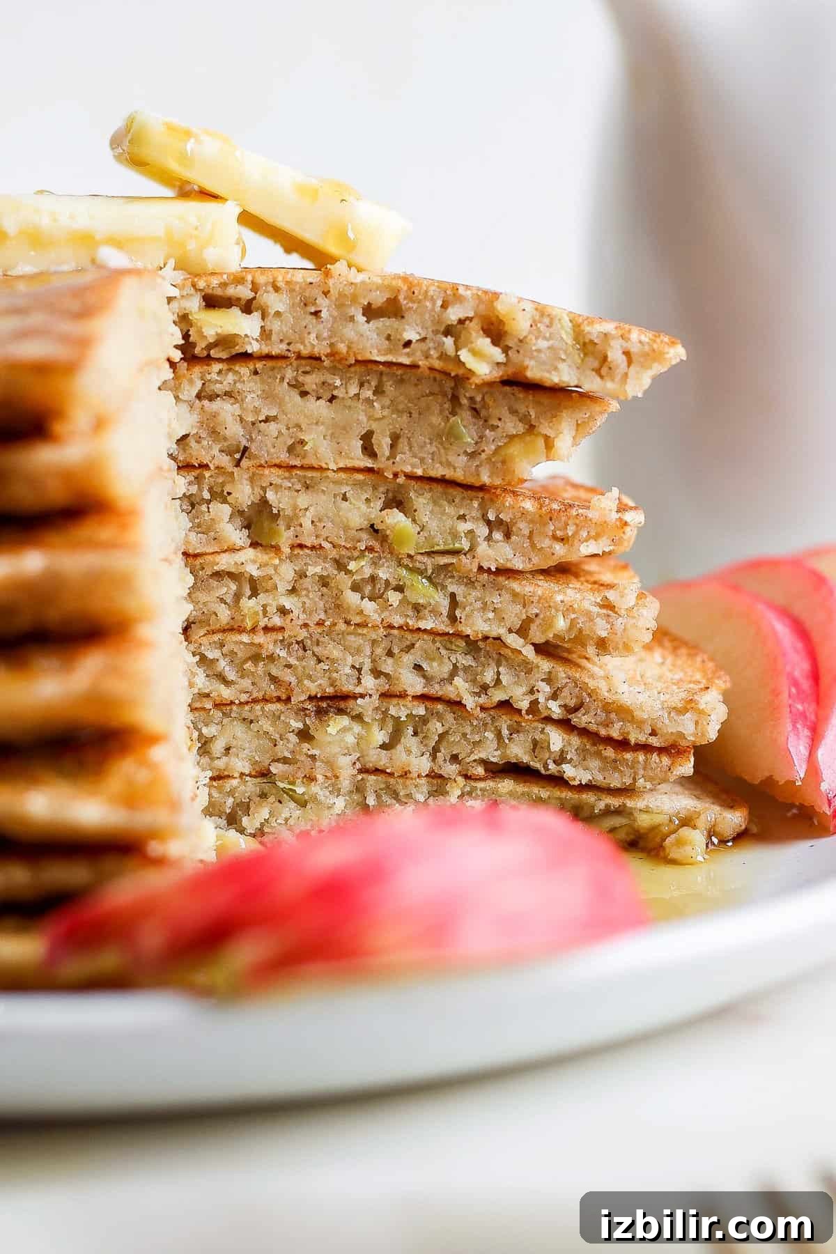 Fluffy Cinnamon Apple Pancakes with Caramel Sauce 7 a stack of pancakes on a plate with apple slices.