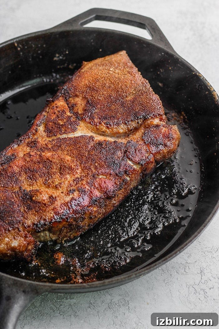 Searing pork shoulder before slow cooking. searing pork roast in cast iron skillet.