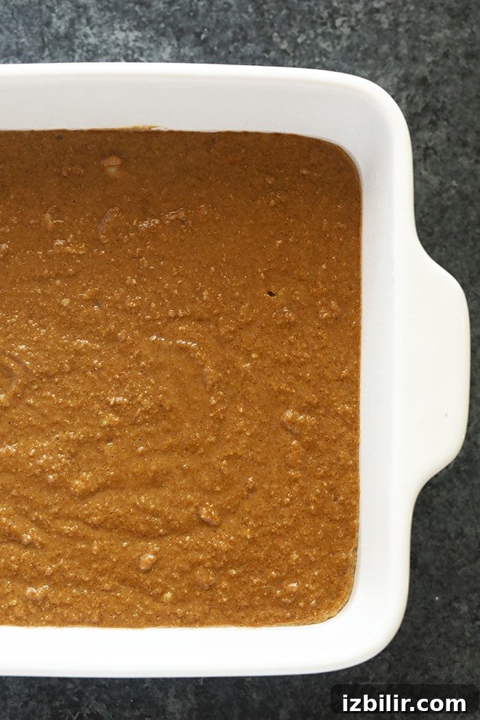 This classic Gingerbread Recipe is calling your name this holiday season! Perfectly spiced and sweet, and topped with a delicious lightened-up cream cheese frosting. Dessert is served! gingerbread in a square baking pan ready to be put in the oven