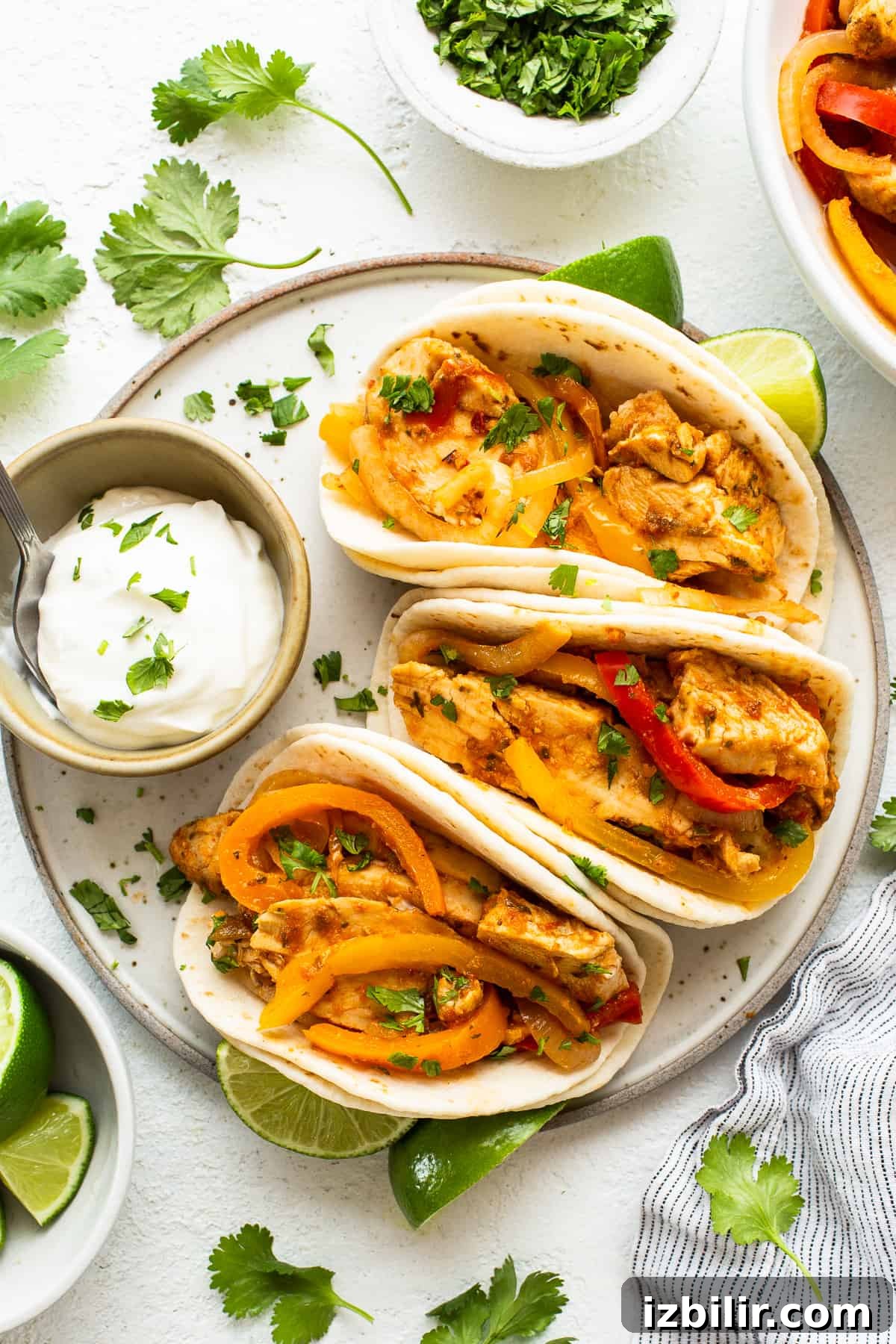 Slow Cooker Chicken Fajitas with Bell Peppers 2 Chicken fajita tacos on a plate with limes and sour cream.