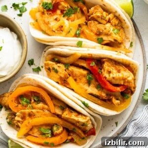 Slow Cooker Chicken Fajitas with Bell Peppers 10 Three chicken tacos with peppers and sour cream on a plate.