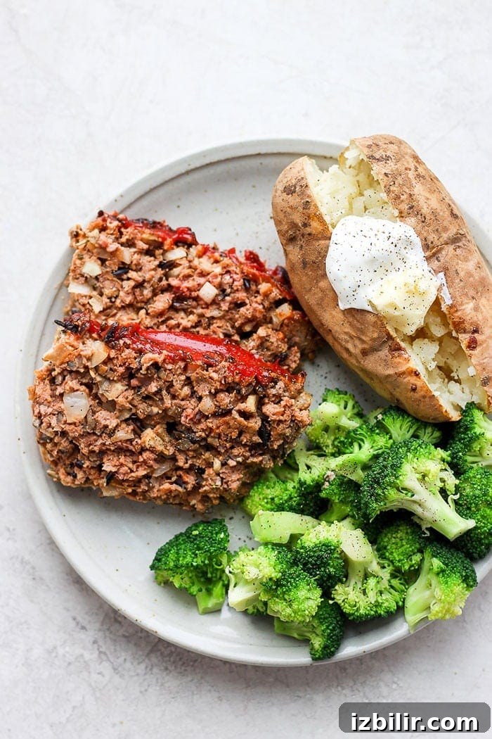 wild rice meatloaf on a plate with a baked potato and broccoli