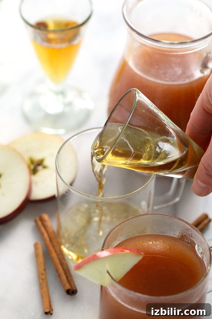 Hot Spiked Apple Cider with Bourbon and Cinnamon 4 shot of booze being poured in a mug for spiked apple cider