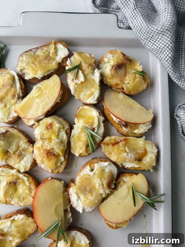 How to Roast Garlic for Sweet, Spreadable Cloves 2 Cheesy roasted apple and goat cheese potato wedges with rosemary sprigs on a baking sheet, perfectly complemented by the aroma of roasted garlic.