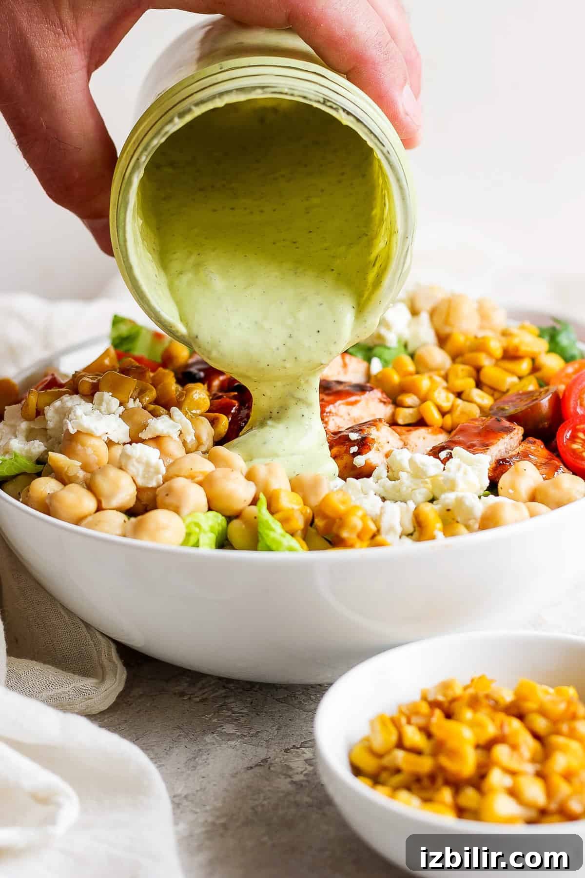 A person pouring a dressing into a bowl of salad.