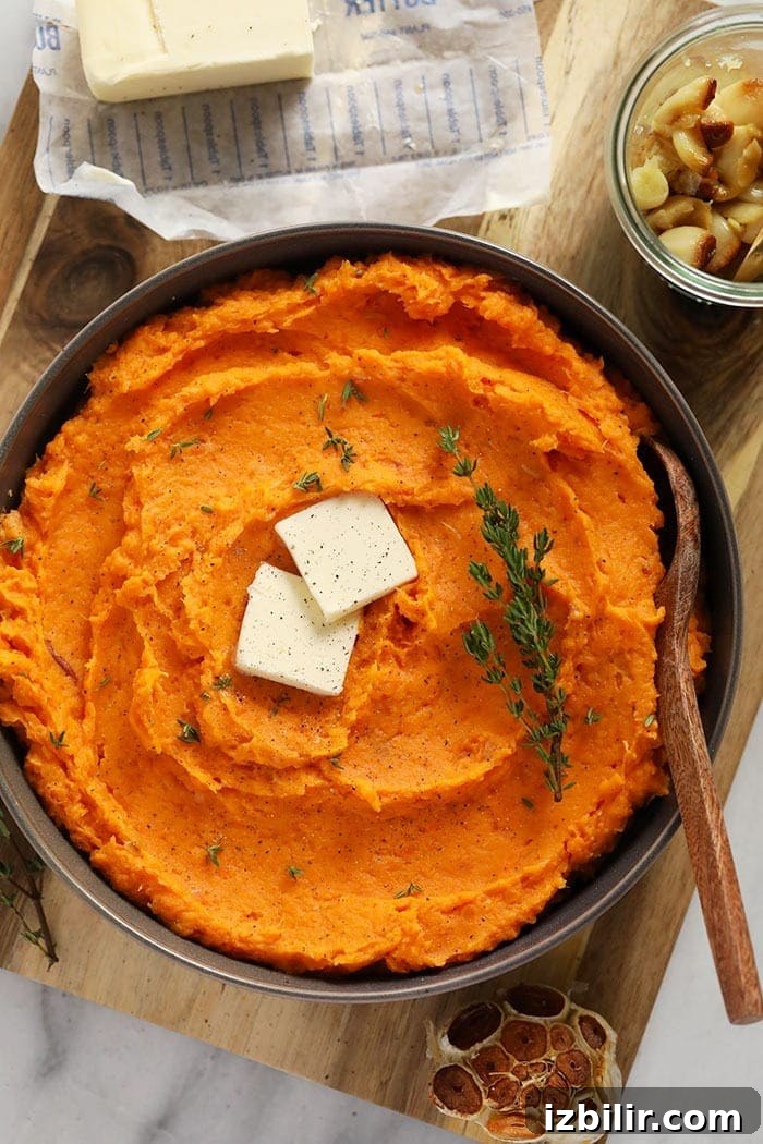 Mashed sweet potatoes are a silky smooth, buttery side made with roasted sweet potatoes, a whole head of garlic, and a little Greek yogurt. healthy mashed sweet potatoes in bowl with butter