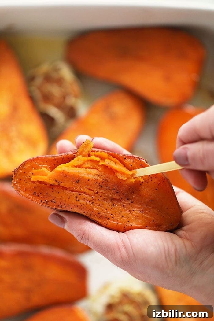 Scooping roasted sweet potato flesh to mash. scooping out sweet potato flesh with spoon