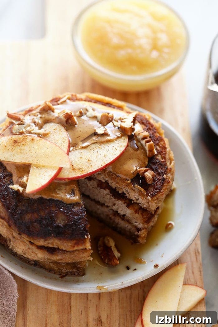 applesauce pancakes on a plate topped with apple slices and nut butter