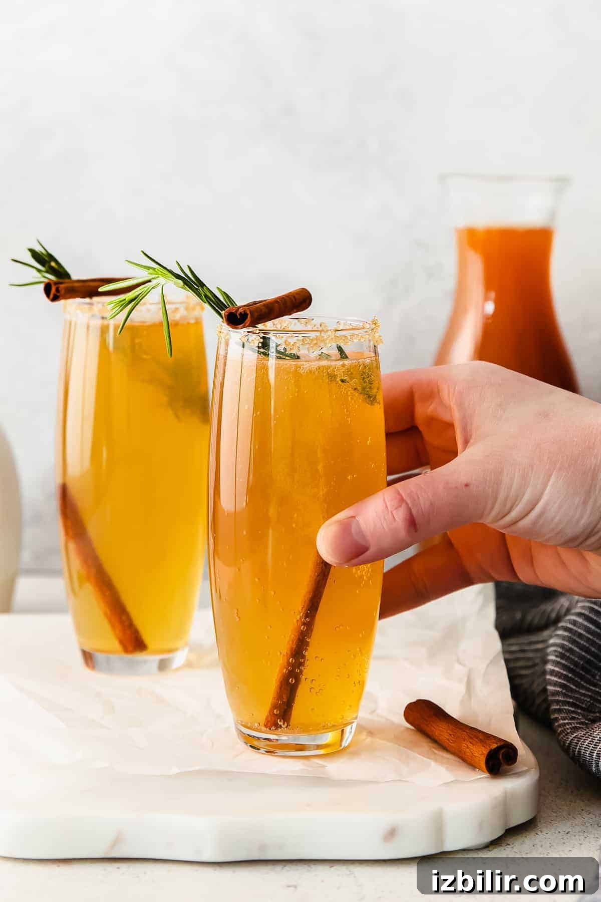 Sparkling Apple Cider Mimosa Recipe for Fall Brunch 2 A hand holding an apple cider mimosa.