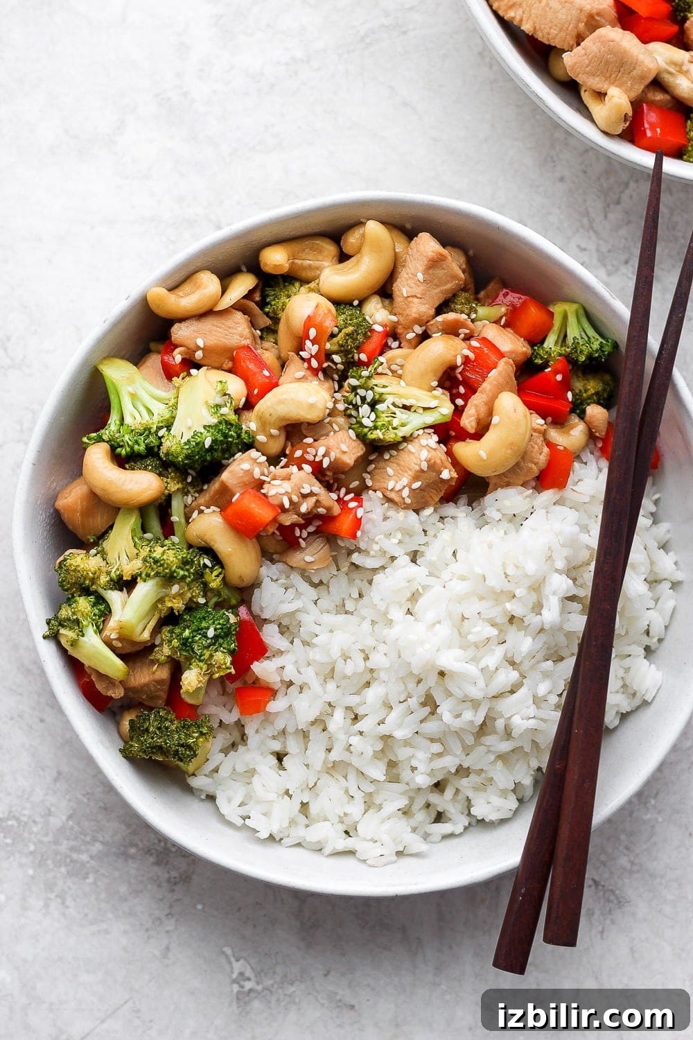 instant pot cashew chicken in a bowl with rice and chopsticks