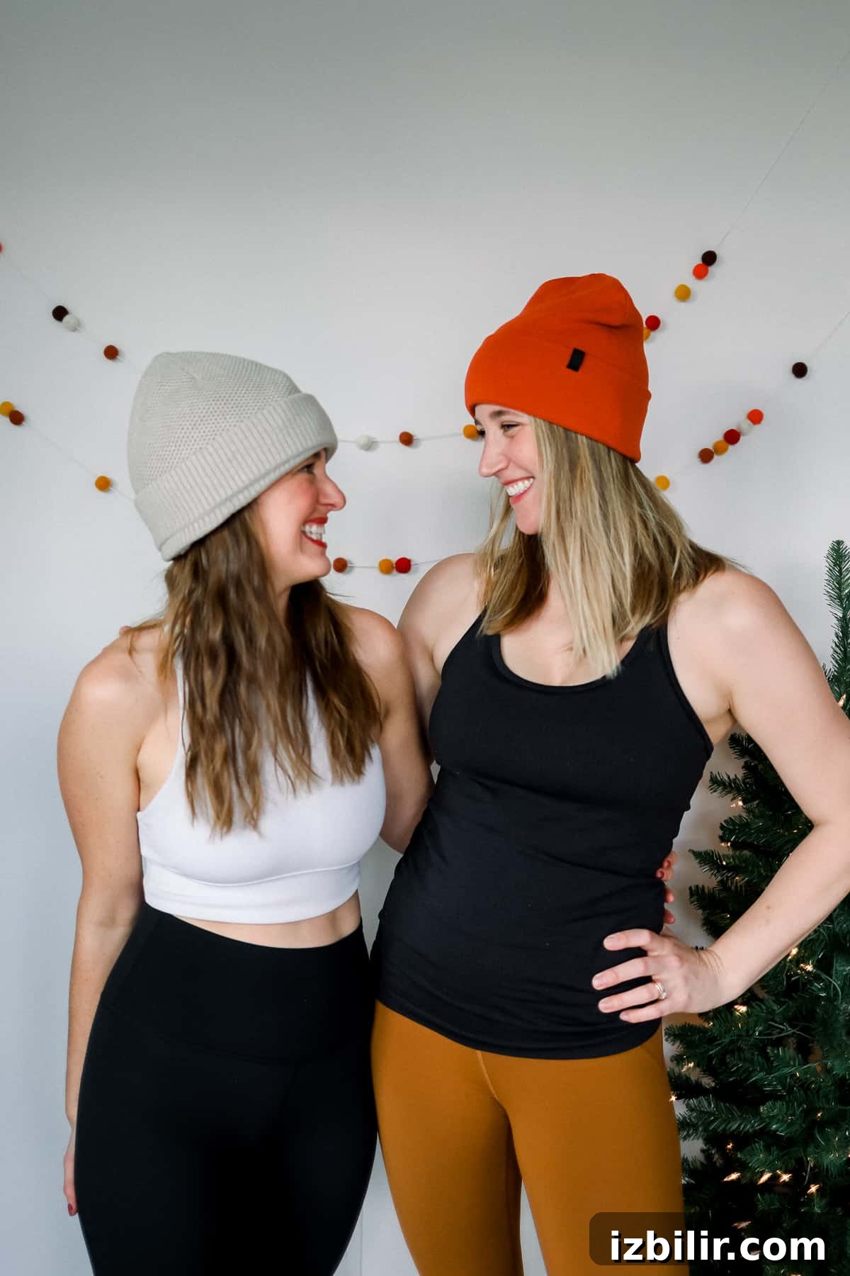 Two women in stocking caps standing by a Christmas tree