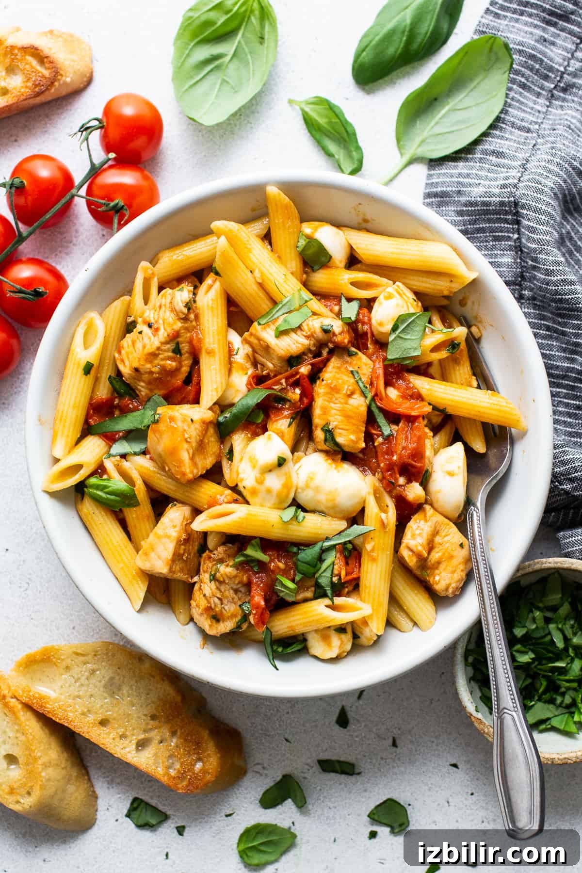 caprese chicken pasta in bowl with crostini on the side.