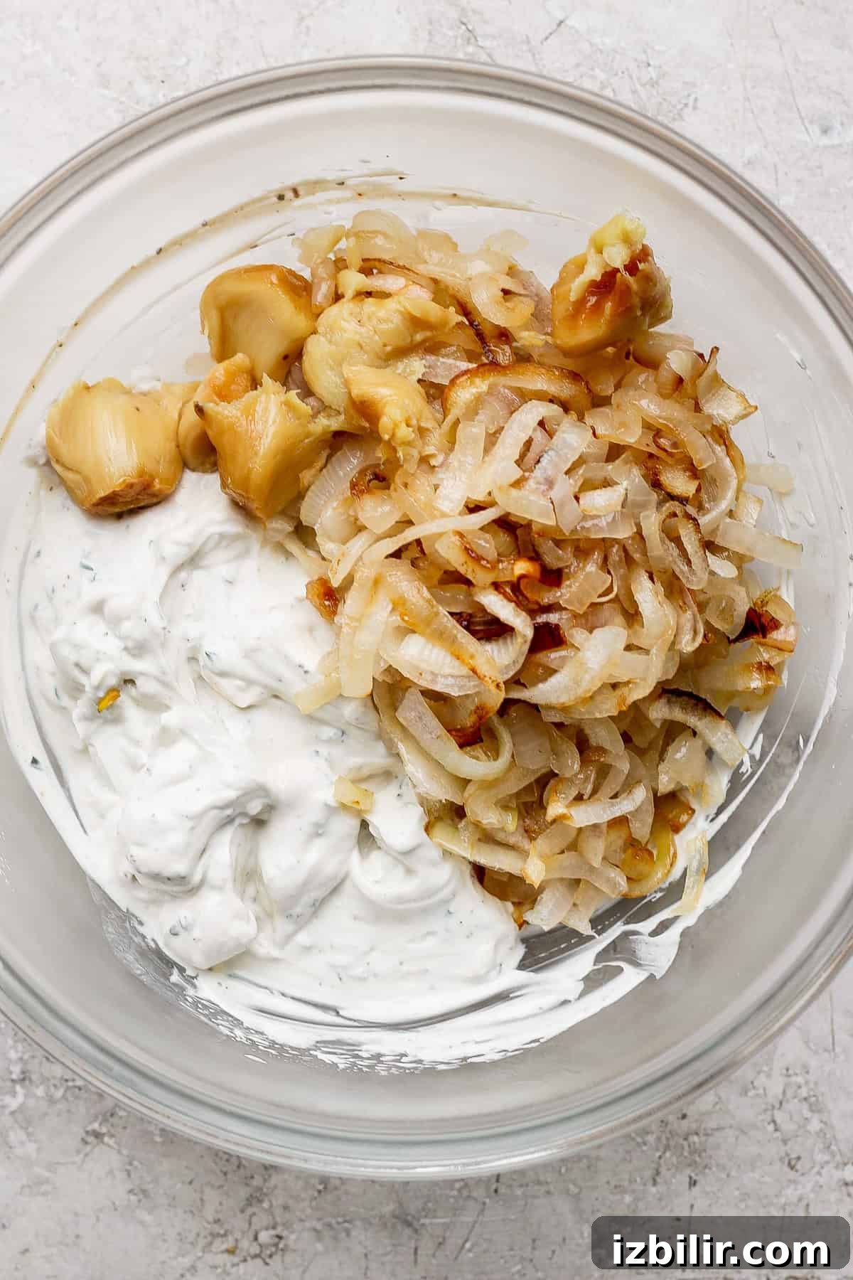 Creamy Caramelized Onion Dip Recipe 2 A bowl contains roasted garlic, caramelized onions, and herb-infused creamy dip.