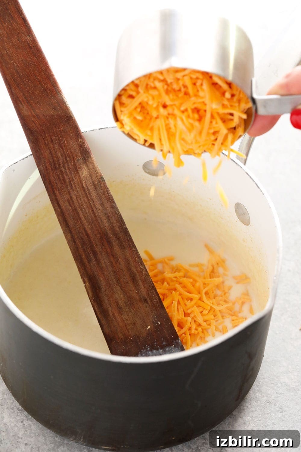 Mixing the cheese sauce cauliflower mac and cheese sauce being mixed in a pot