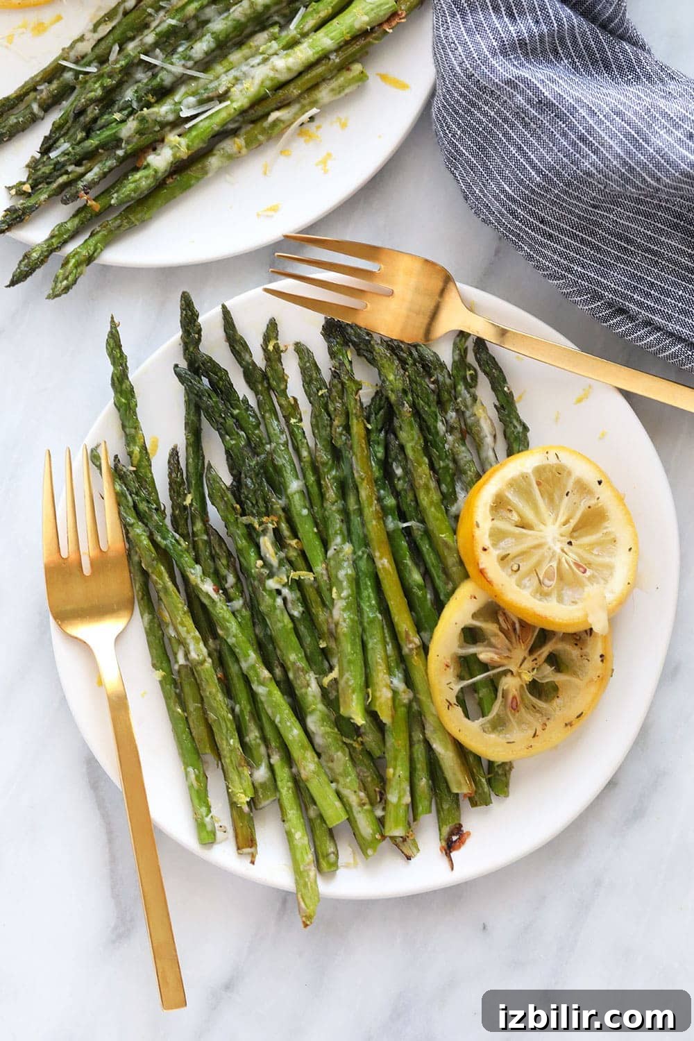 Oven roasted asparagus with parmesan cheese is the best way to eat asparagus! It's a healthy side dish recipe that's cooked to perfection. Asparagus on plate with lemon zest garnish.