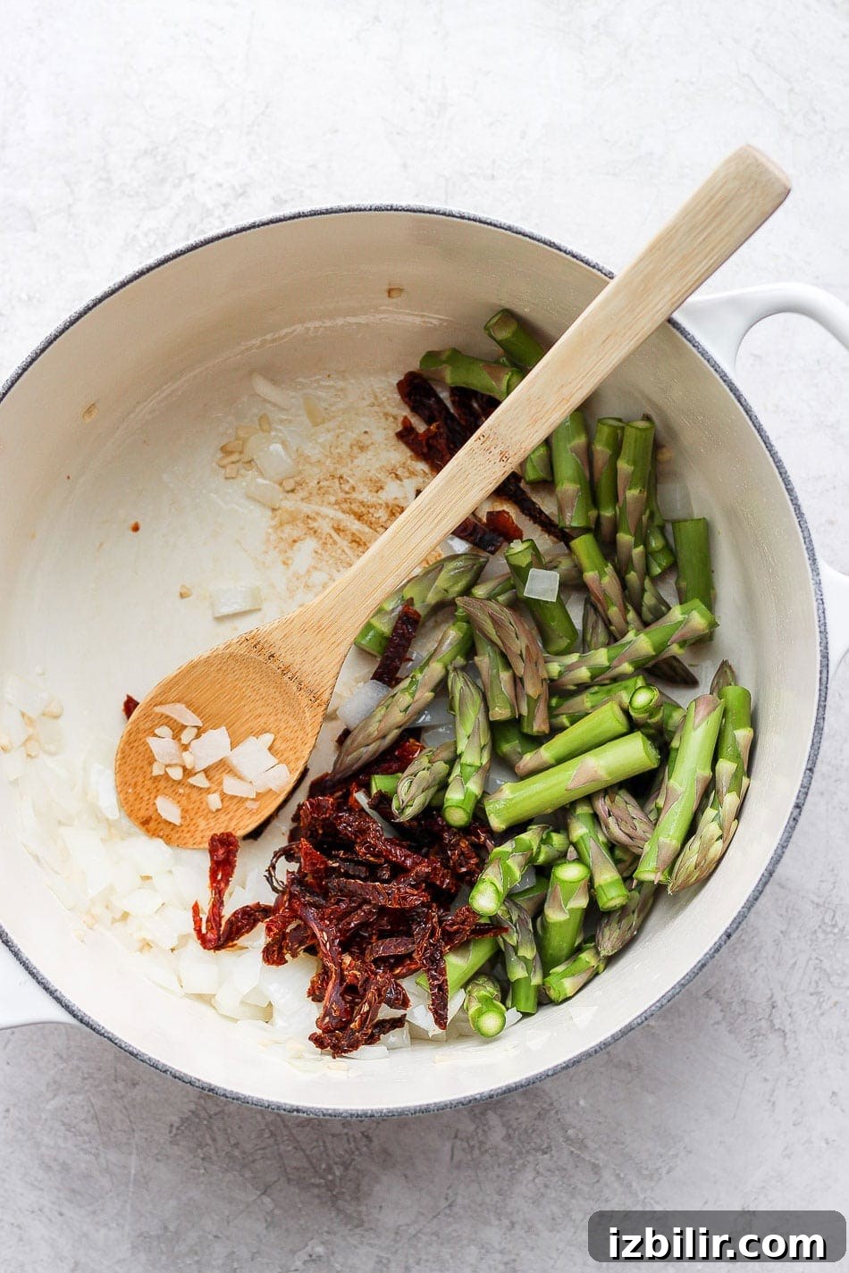 Creamy Vegan Asparagus Pasta Recipe 4 asparagus, sun-dried tomatoes and onions in a dutch oven ready to be sauteed