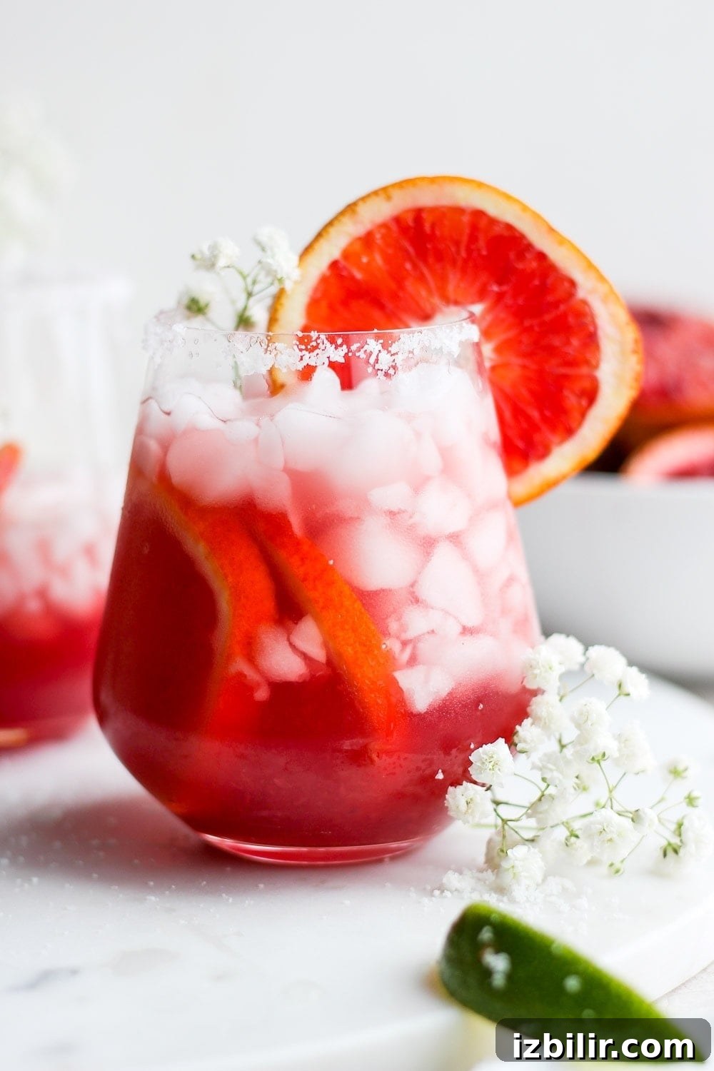 Blood orange margarita served with a salty rim and orange garnish. Blood Orange Margarita in a glass