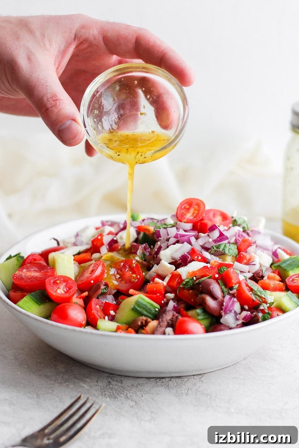 Pouring dressing onto the Greek Salad Pouring dressing onto the Greek Salad