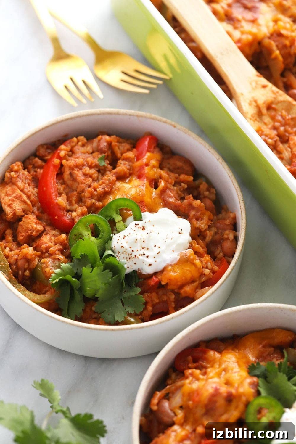 Healthy Chicken Burrito Bowl Casserole healthy chicken burrito bowl casserole in a bowl topped with sliced jalapenos and a dollop of greek yogurt