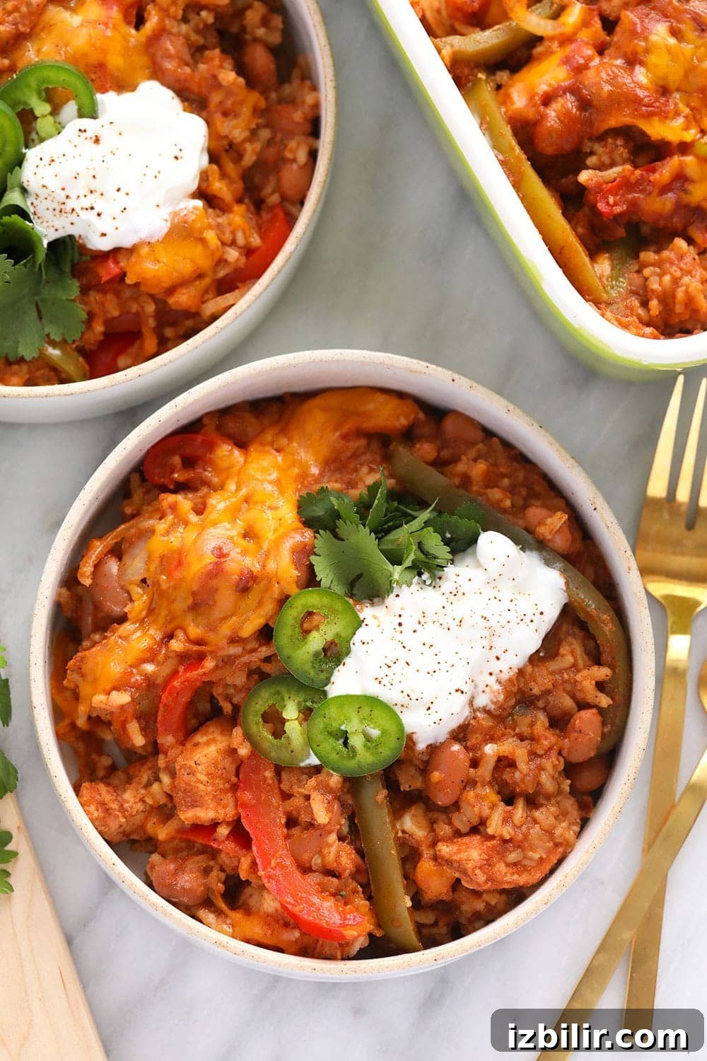 Chicken Burrito Bowl Casserole Served in a Bowl chicken burrito bowl casserole in a bowl topped with sliced jalapeños and a dollop of greek yogurt