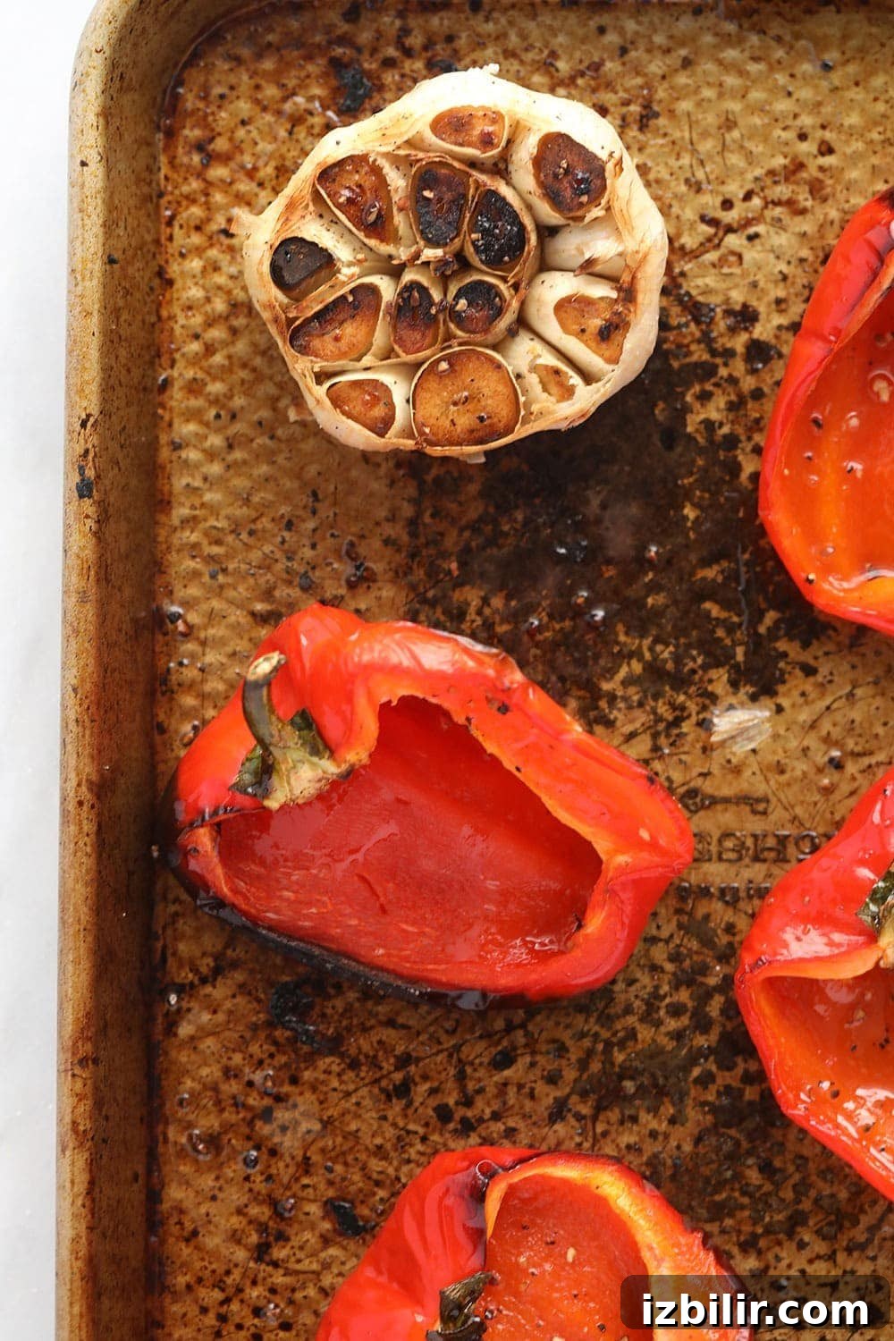 Roasted peppers and garlic for hummus red peppers and garlic cloves ready to be roasted on a baking sheet