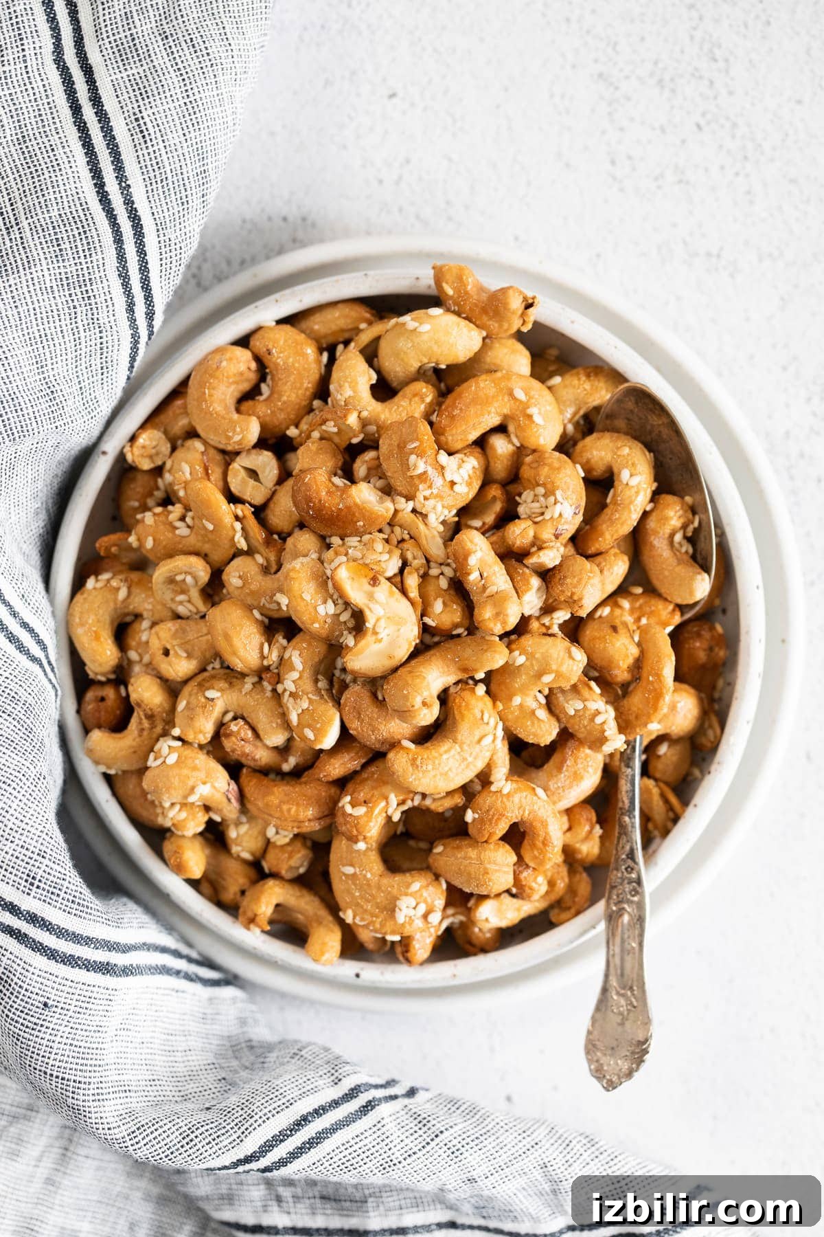 roasted cashews with sesame seeds in a bowl with a spoon