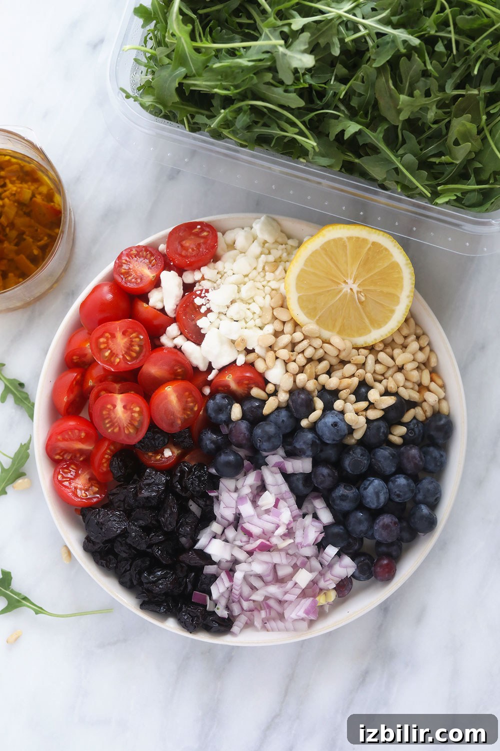 This arugula salad has dried fruit, vegetables, cheese, and a delicious dressing! All of the ingredients for the arugula salad on a plate