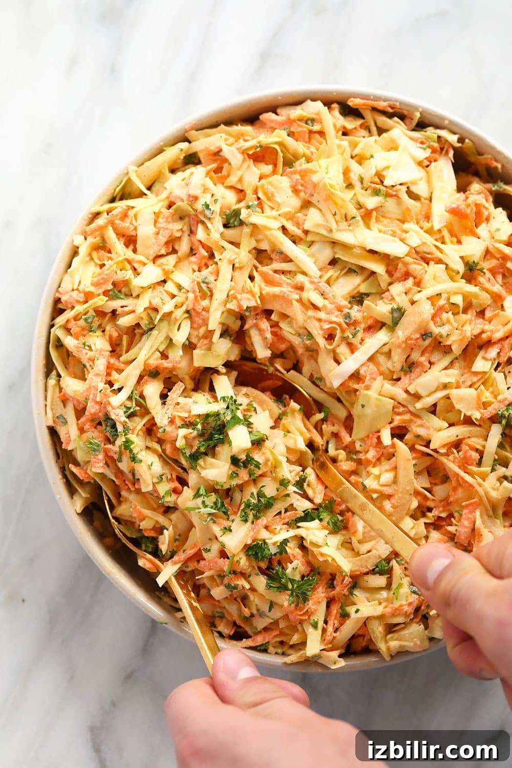 creamy coleslaw in a bowl being served with serving spoons