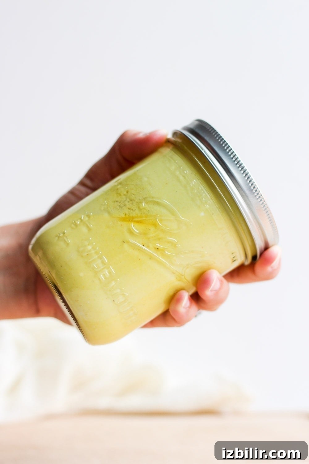 hand shaking honey mustard dressing in jar