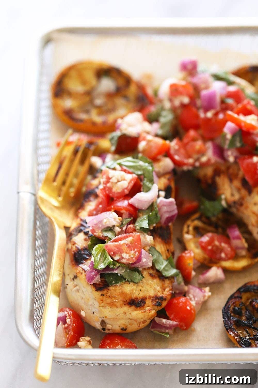 This marinated greek chicken is easy to make and perfect for an easy dinner or a meal prep lunch! Lemon Greek chicken with fresh tomatoes on top.