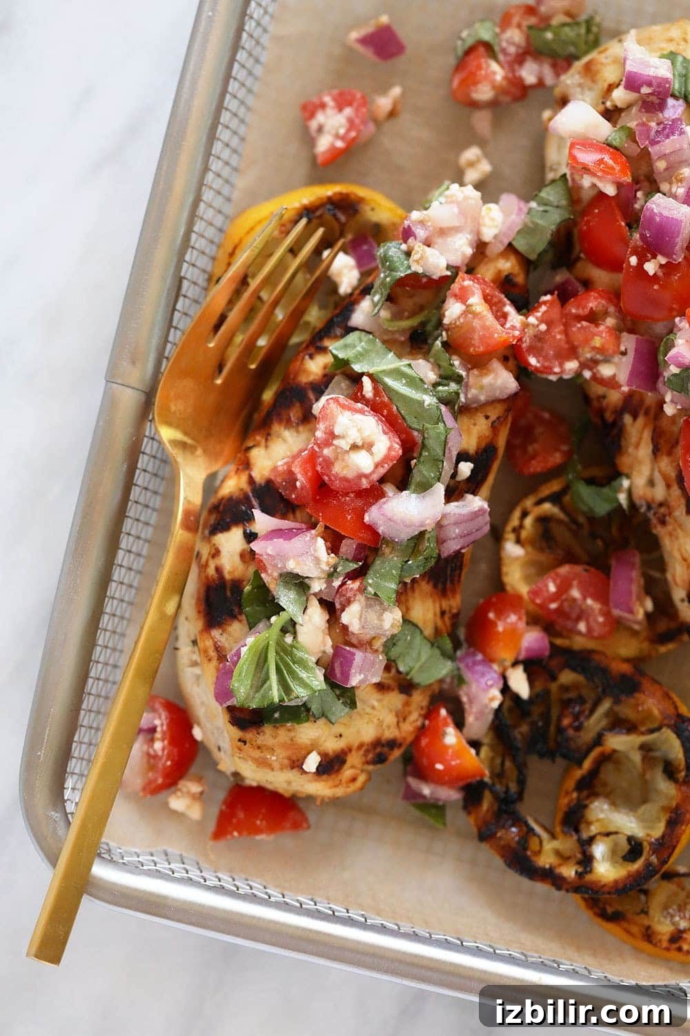 Grilled lemon Greek Chicken with a fresh Greek salad makes a perfect, healthy, and easy dinner! Grilled Greek lemon chicken with Greek salad on top.