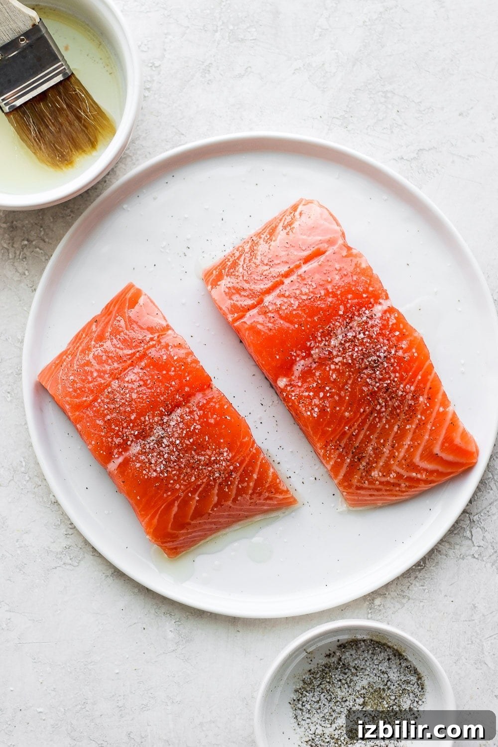 raw salmon filets being brushed with olive oil