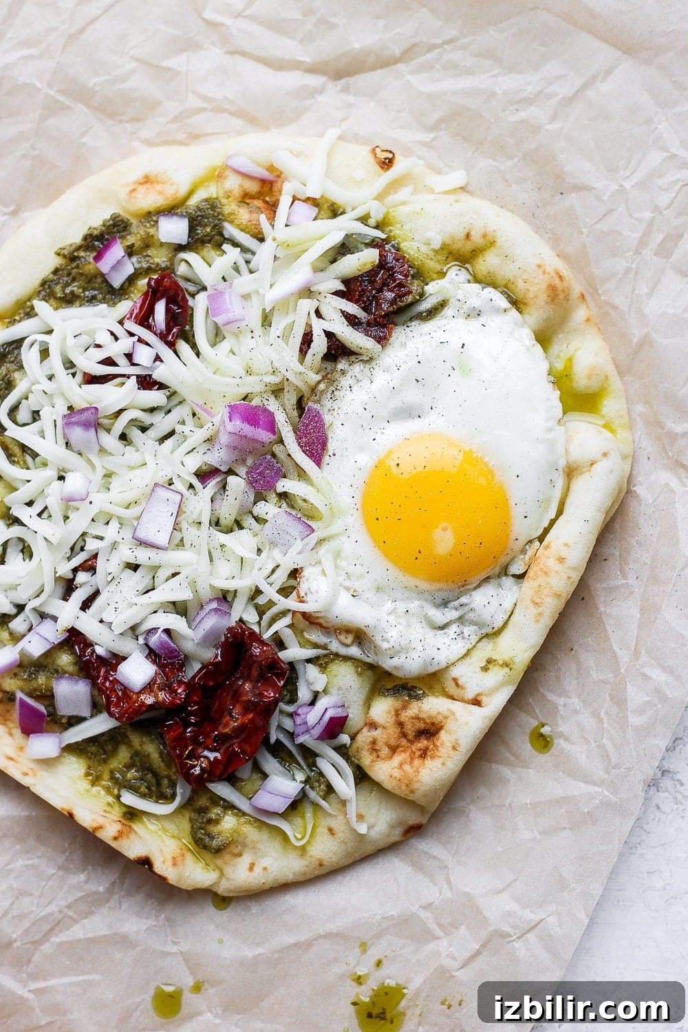 Crispy Naan Breakfast Pizza Recipe with Eggs and Cheese 5 Naan pizza topped with pesto, sun dried tomatoes, cheese, and a fried egg.