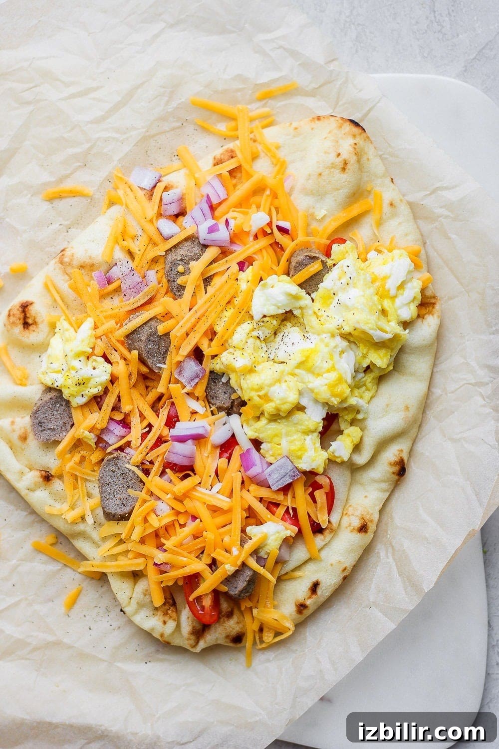 Crispy Naan Breakfast Pizza Recipe with Eggs and Cheese 6 Naan pizza topped with scrambled eggs, cheese, sausage, and onions.