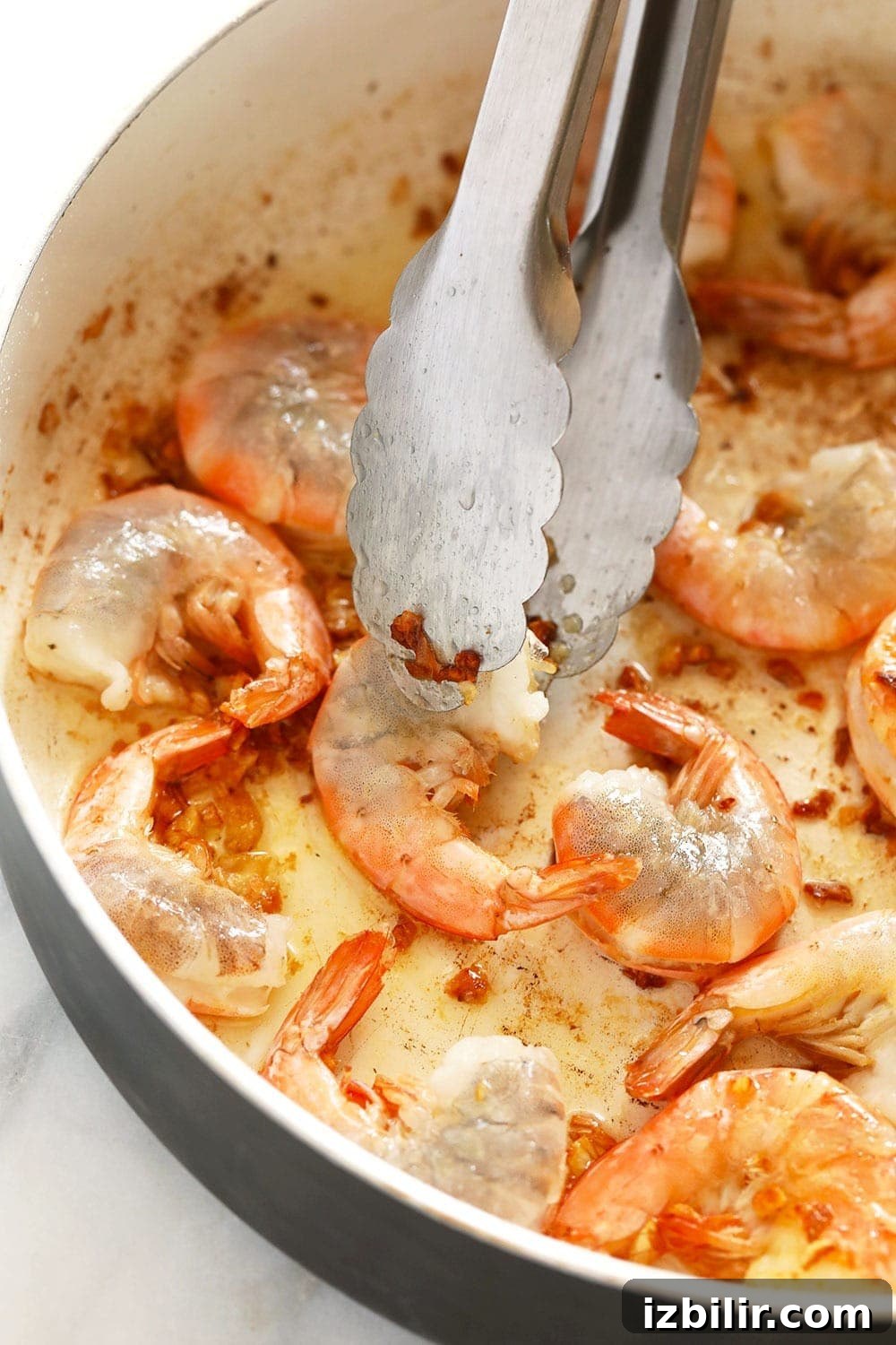 Sautéing garlic butter shrimp in a skillet garlic butter shrimp in a skillet being flipped with tongs