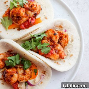 Crispy Shrimp Tacos with Lime Slaw and Avocado Crema 2 Three shrimp tacos on a white plate.