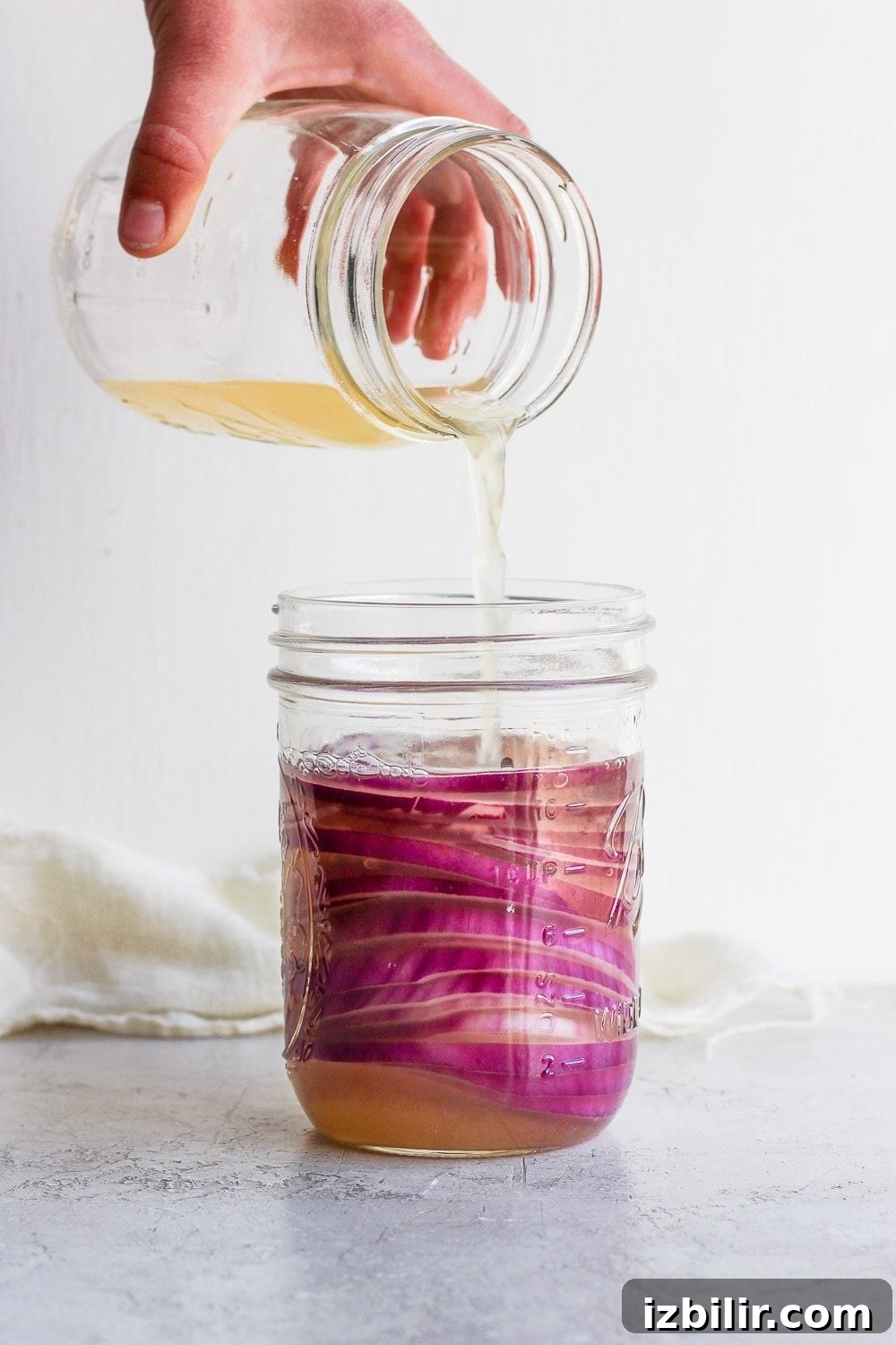 Pouring vinegar over sliced onions Pouring vinegar into the mason jar with onions