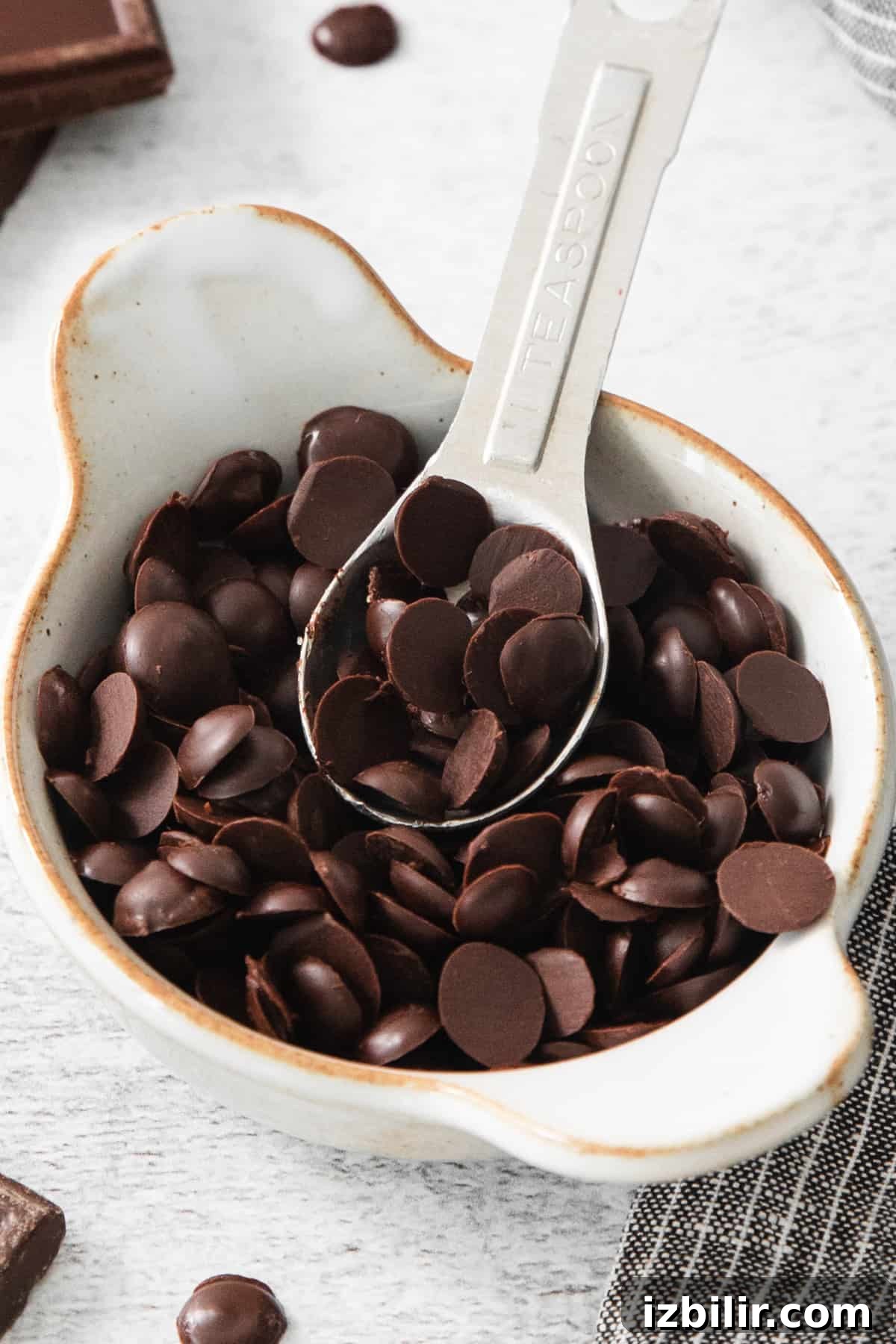 How to Make Homemade Vegan Chocolate Chips 2 Chocolate chips in a white bowl with a spoon.